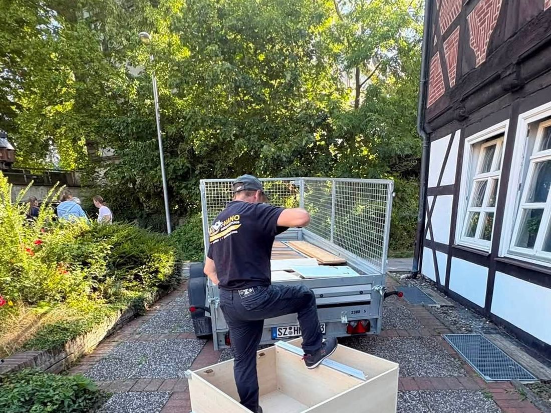 HANO-Mitarbeiter am Anhänger vor einem Fachwerkhaus