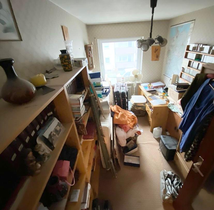 Arbeitszimmer mit Regal, Schreibtisch und vielen Unterlagen