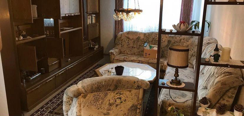 Möbliertes Wohnzimmer mit Schrankwand und Sitzgruppe vor der Räumung