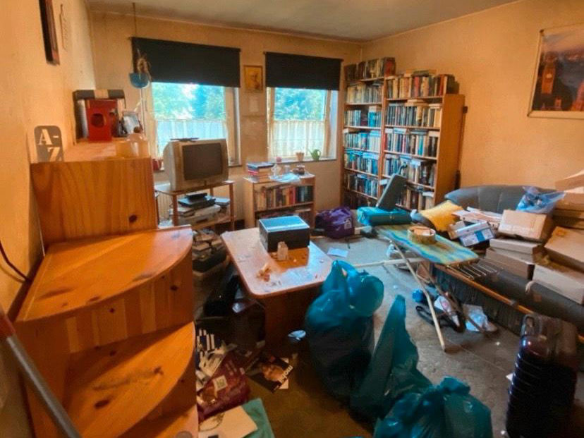 Zimmer mit Möbeln, Büchern und Müllsäcken vor der Räumung