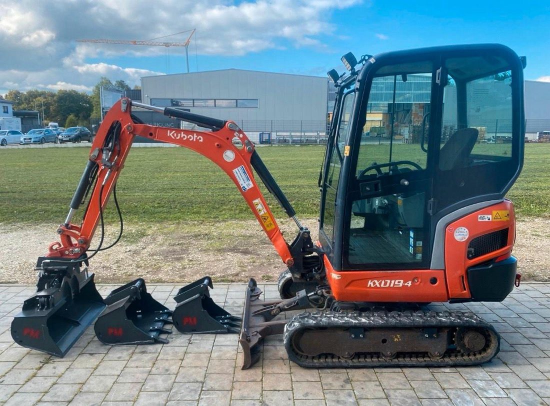 Orangefarbener Minibagger Kubota KX019-4 mit Kabine auf einer Wiese