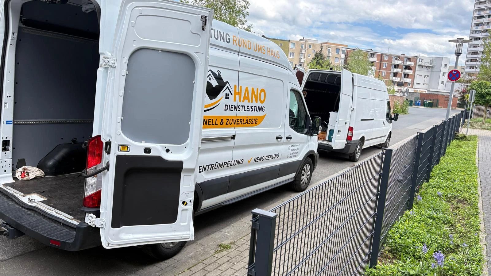 Weißer HANO-Transporter mit geöffneten Hecktüren am Straßenrand, dahinter ein zweiter Transporter