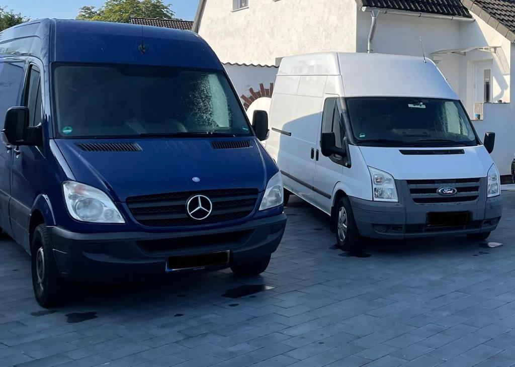Zwei Transporter von HANO-Dienstleistung, ein dunkelblauer Mercedes und ein weißer Ford, auf einem Hof