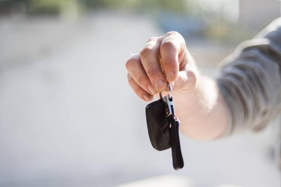 Hand hält einen Autoschlüssel zur Übergabe bereit